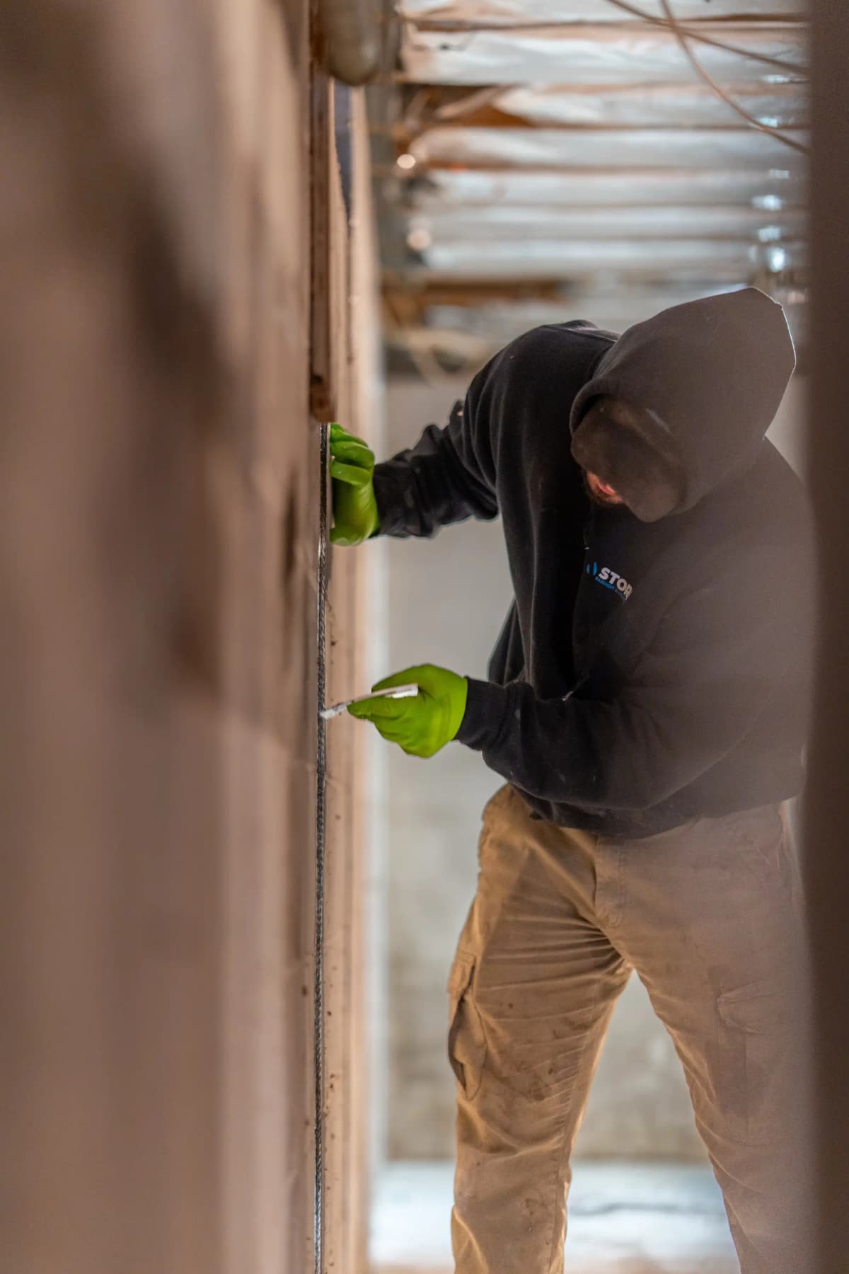 Professional installing carbon fiber reinforcement on basement wall